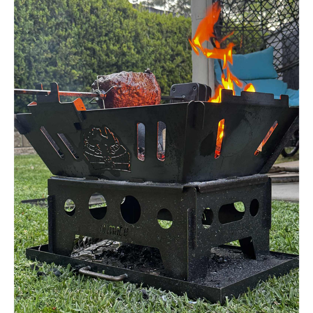 Ol Mate fire pit BBQ with rotisserie cooking over open flame in backyard setting