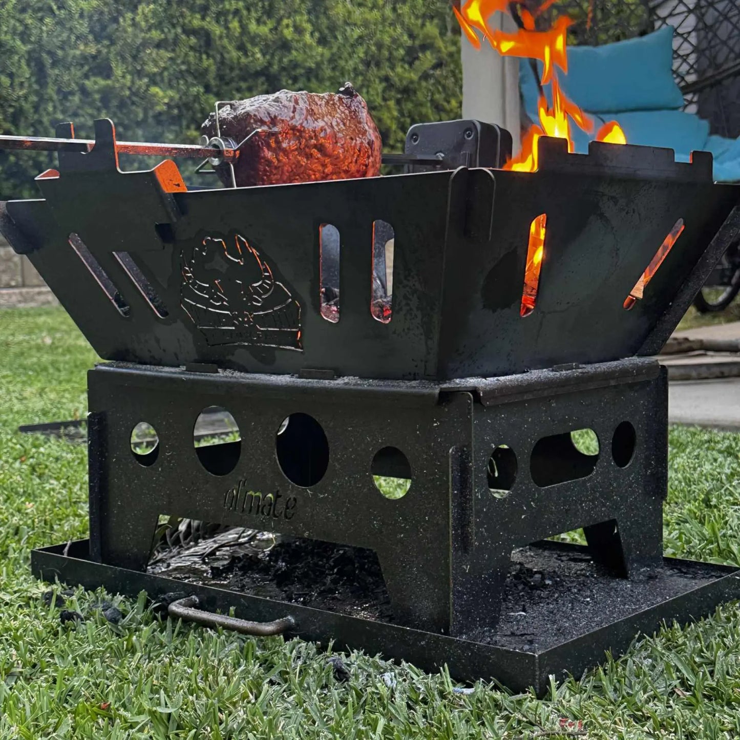 Ol'Mate portable camping fire pit cooking a roast on a rotisserie